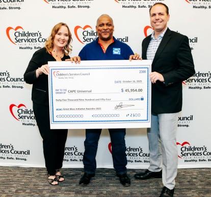 CSC CEO Lisa Williams-Taylor and Board Chair Thomas Bean stand in front of CSC's step-and-repeat sign with a Great Ideas Initiative recipient holding an oversized check during the October 2025 celebration.
