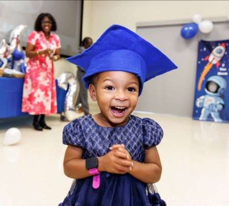 A little girl with a blue graduation cap smiles at the Nurse-Family Partnership graduation event in 2025.