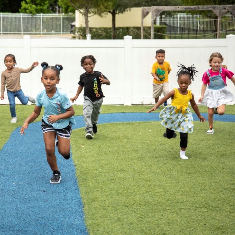 Children attending a voluntary prekindergarten program outside running toward the camera.